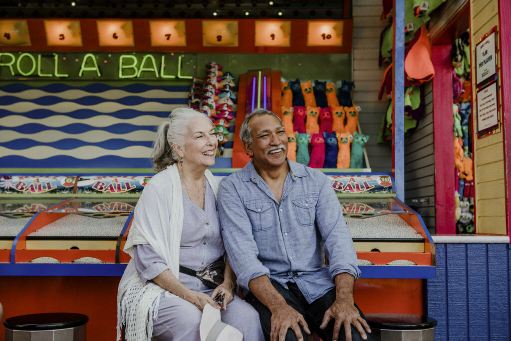 Happy senior couple sitting by a game stall